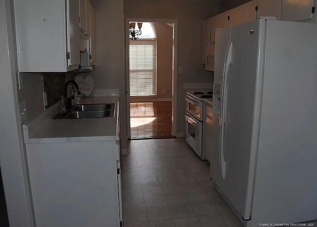 kitchen with light countertops, white appliances, a sink, and white cabinetry