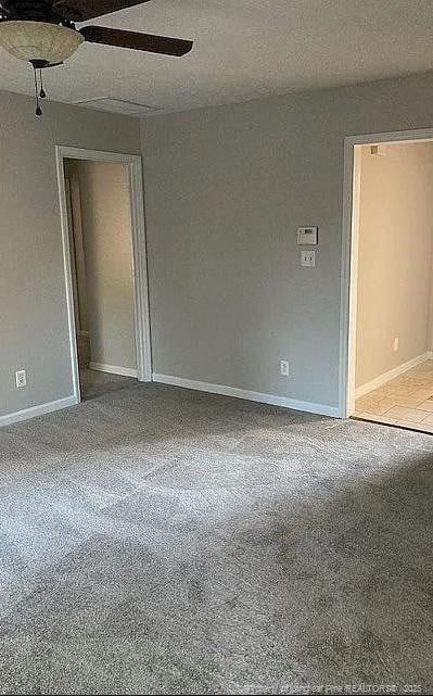 carpeted spare room with ceiling fan, a textured ceiling, and baseboards