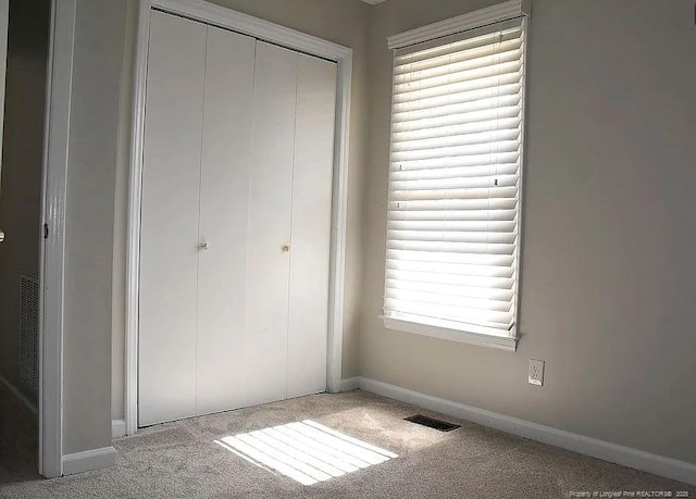 unfurnished bedroom featuring a closet, baseboards, visible vents, and carpet flooring