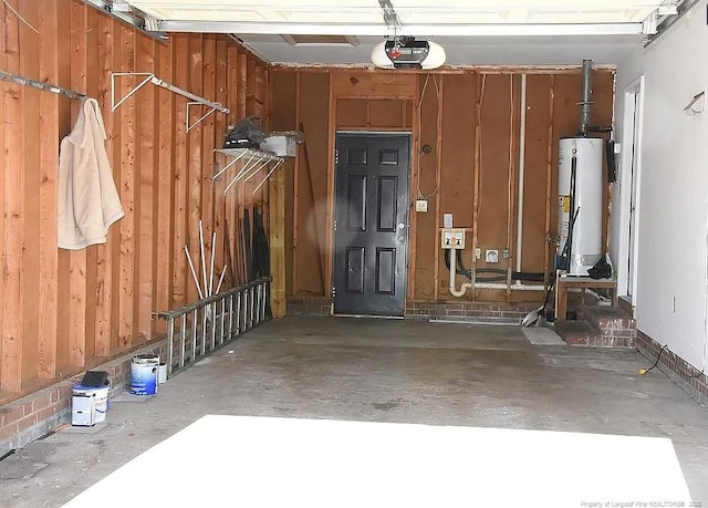 garage featuring water heater, a garage door opener, and wooden walls