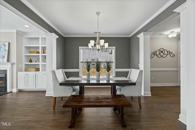 dining space with dark wood-style flooring, baseboards, an inviting chandelier, a glass covered fireplace, and crown molding