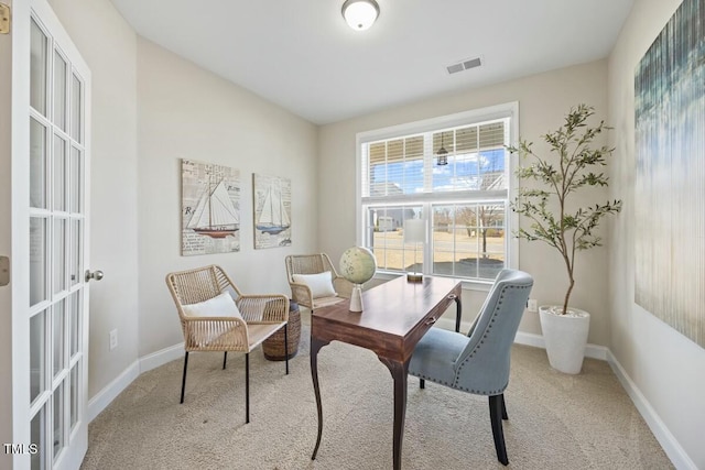 office space with baseboards, visible vents, and light colored carpet