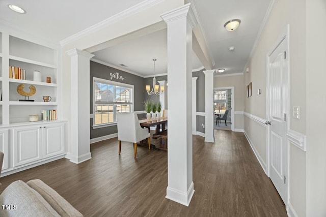 interior space with baseboards, built in features, dark wood finished floors, crown molding, and ornate columns