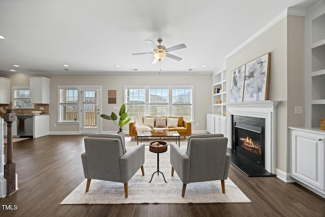 living room with baseboards, ornamental molding, dark wood-style flooring, and a glass covered fireplace