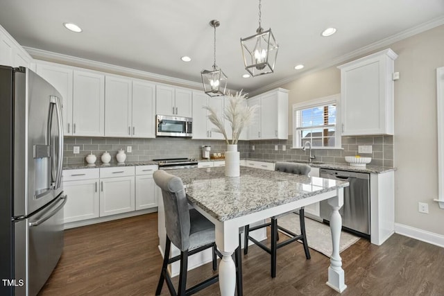 kitchen with appliances with stainless steel finishes, light stone counters, decorative light fixtures, crown molding, and white cabinetry