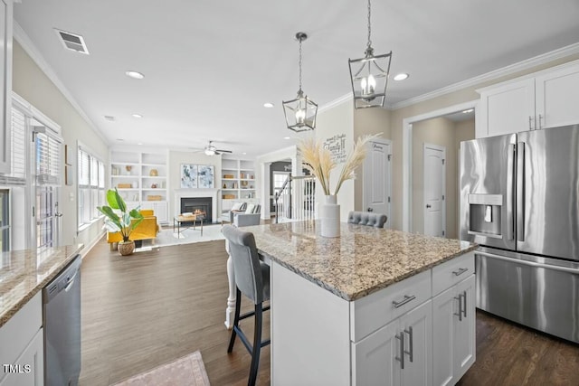 kitchen featuring appliances with stainless steel finishes, open floor plan, white cabinets, and a kitchen island