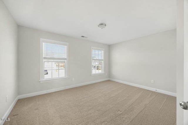 spare room featuring carpet, visible vents, and baseboards