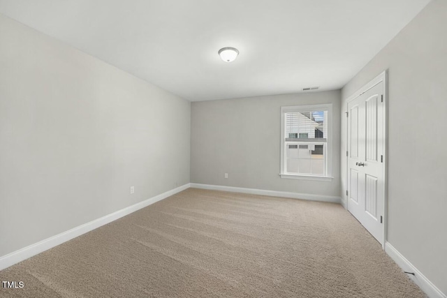 carpeted spare room with visible vents and baseboards