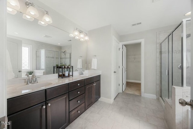 bathroom with a stall shower, a walk in closet, and a sink