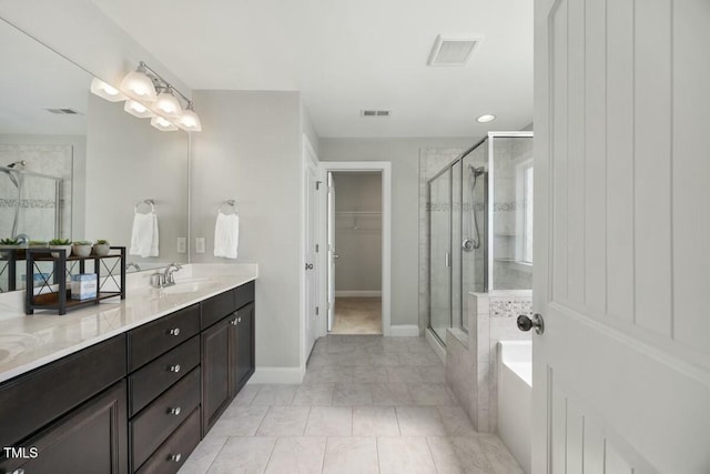 bathroom with double vanity, visible vents, a walk in closet, a shower stall, and a sink