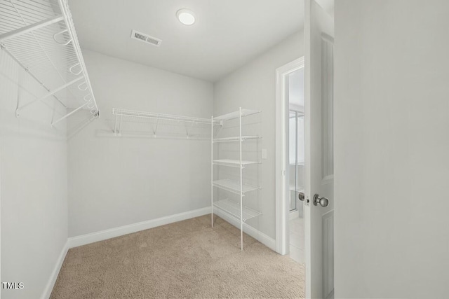 walk in closet with visible vents and light colored carpet