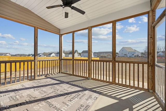 unfurnished sunroom featuring a ceiling fan, a residential view, and vaulted ceiling