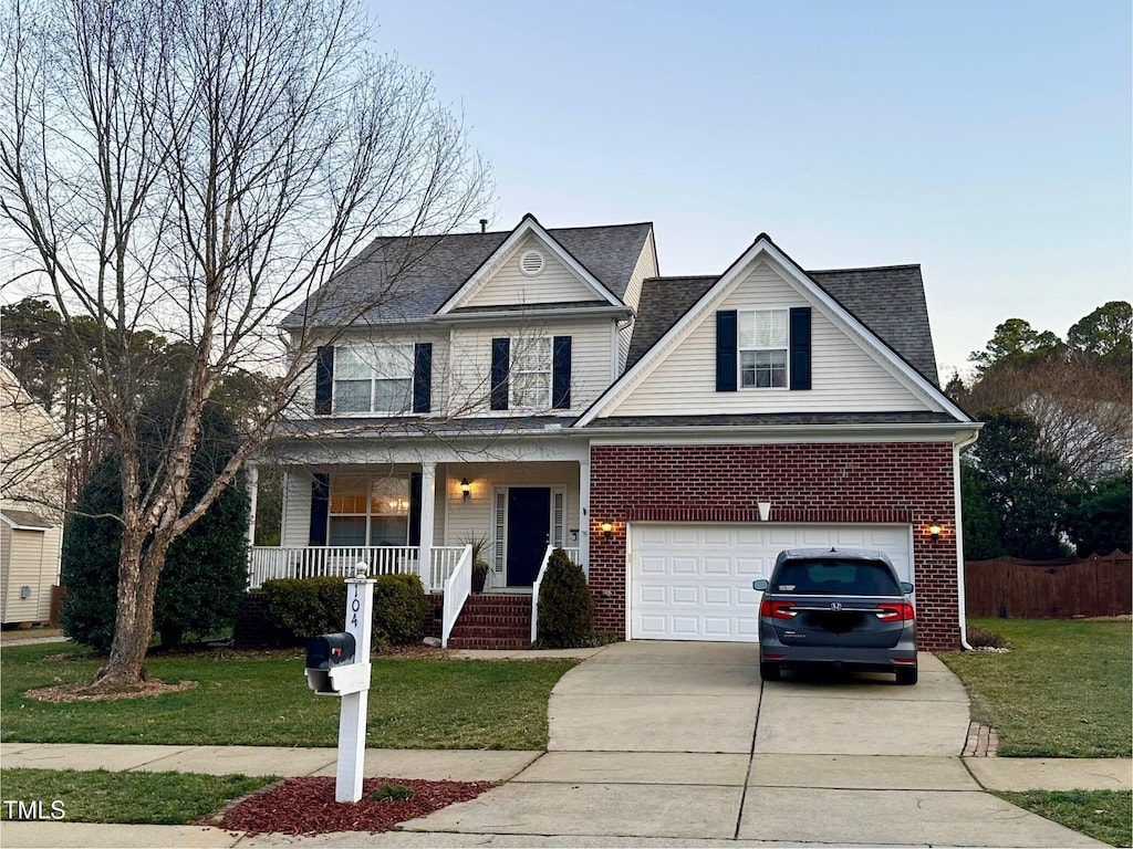 traditional-style home featuring a porch, a front yard, brick siding, and driveway