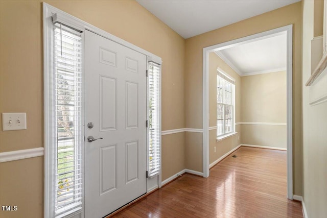 entrance foyer featuring ornamental molding, wood finished floors, and baseboards