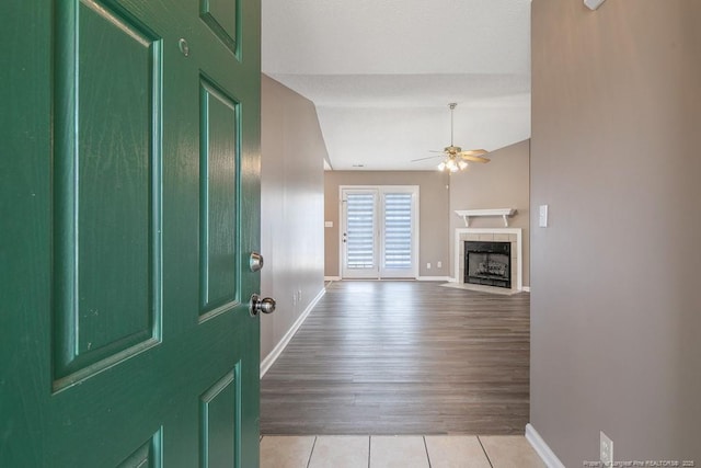 foyer with ceiling fan, light tile patterned floors, baseboards, vaulted ceiling, and a tiled fireplace