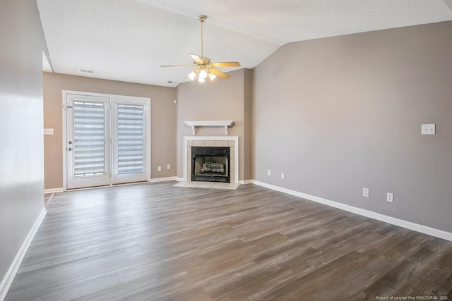 unfurnished living room with lofted ceiling, a fireplace, baseboards, and wood finished floors