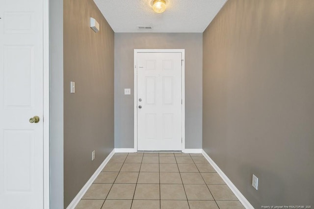 entryway featuring visible vents, light tile patterned flooring, a textured ceiling, and baseboards