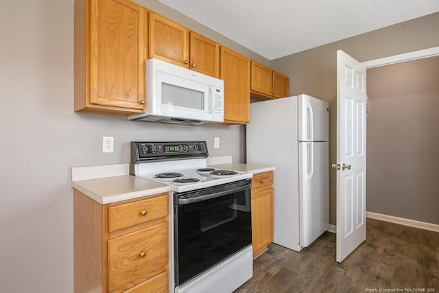 kitchen featuring dark wood finished floors, light countertops, a textured ceiling, white appliances, and baseboards