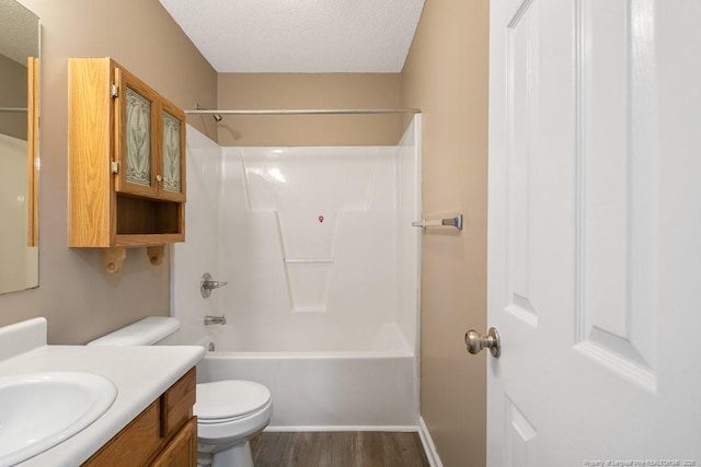 full bathroom featuring toilet, wood finished floors, a textured ceiling, vanity, and washtub / shower combination