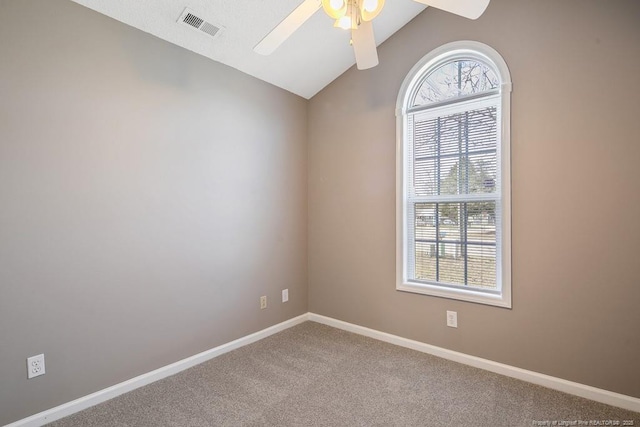 carpeted spare room with a healthy amount of sunlight, visible vents, vaulted ceiling, and baseboards