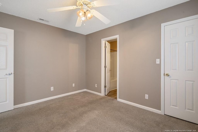 unfurnished bedroom with ceiling fan, light carpet, visible vents, baseboards, and ensuite bath