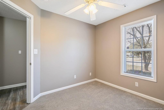 unfurnished room with ceiling fan, baseboards, and dark colored carpet