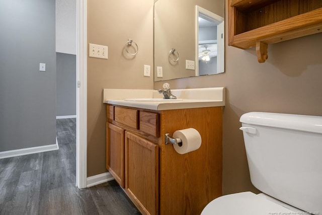 bathroom featuring baseboards, vanity, toilet, and wood finished floors