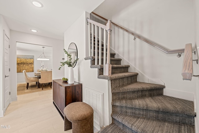 staircase featuring recessed lighting, visible vents, baseboards, and wood finished floors