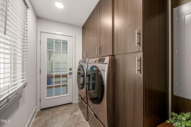 clothes washing area featuring electric panel, cabinet space, baseboards, and washing machine and clothes dryer