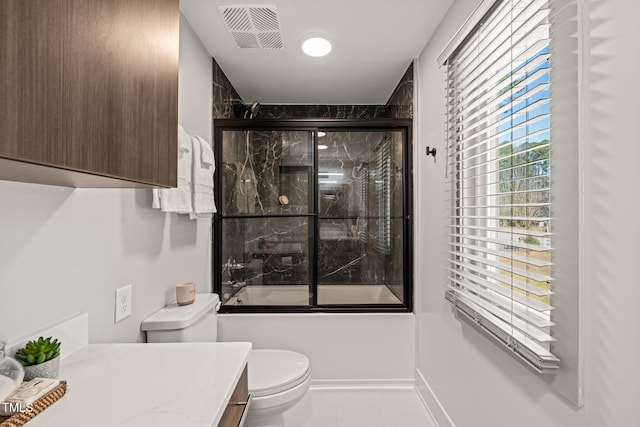 bathroom featuring toilet, vanity, visible vents, baseboards, and combined bath / shower with glass door