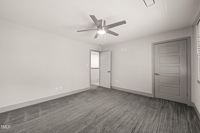 spare room featuring baseboards, dark carpet, and a ceiling fan