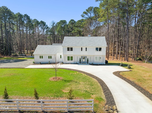 view of front of home with concrete driveway, fence, and a front lawn