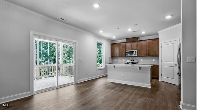 7521 Percussion Dr, Apex, NC 27539 - kitchen featuring stainless steel appliances, ornamental molding, dark wood finished floors, light countertops, and an island with sink