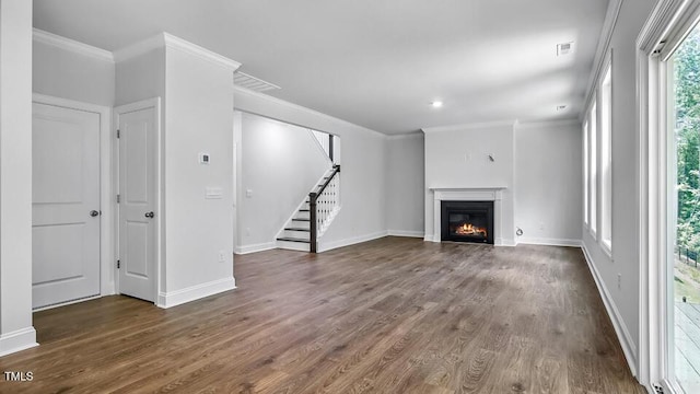 7521 Percussion Dr, Apex, NC 27539 - unfurnished living room with crown molding, wood finished floors, stairs, a glass covered fireplace, and recessed lighting