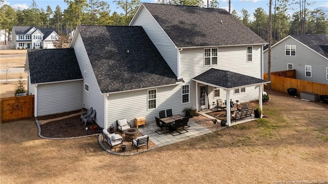 back of property with a patio area, a shingled roof, fence, and a lawn