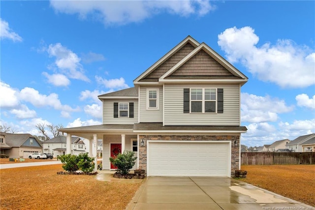 craftsman house featuring concrete driveway, an attached garage, fence, a residential view, and stone siding