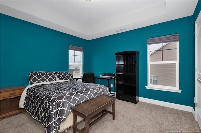 bedroom with light carpet, a tray ceiling, visible vents, and baseboards