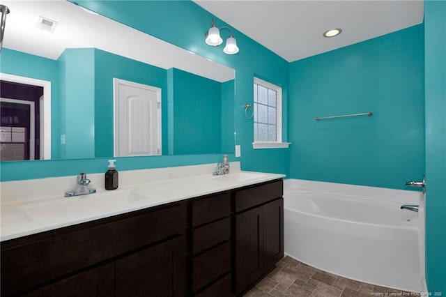 full bath with recessed lighting, a garden tub, a sink, and double vanity