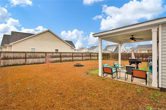 view of yard featuring a fenced backyard, a fire pit, a ceiling fan, a residential view, and a patio area