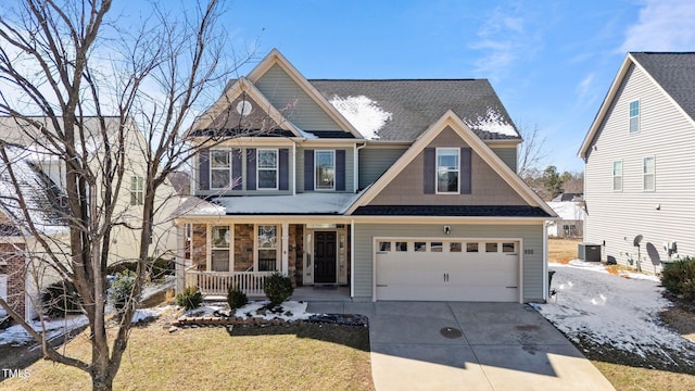 craftsman-style house with a porch, concrete driveway, a front yard, a garage, and cooling unit