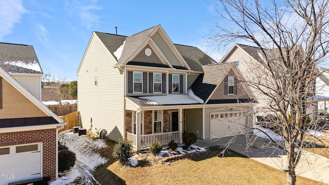 craftsman-style home with an attached garage, covered porch, fence, driveway, and stone siding