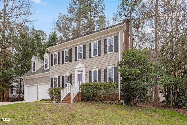 view of front of home featuring a garage, driveway, a chimney, and a front yard