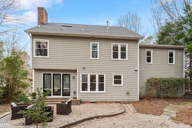 back of property with a chimney, outdoor lounge area, and a patio