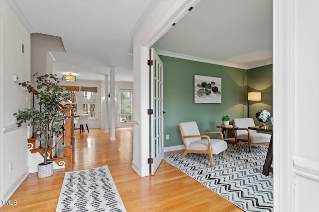 living area with visible vents, wood finished floors, baseboards, and ornamental molding