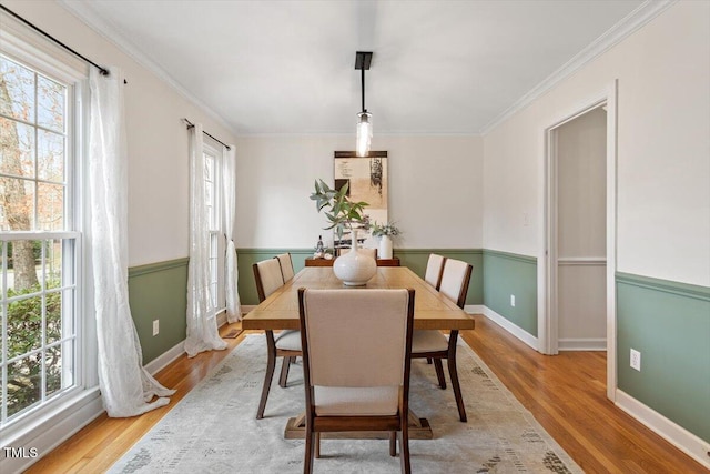 dining space featuring baseboards, light wood-style flooring, and crown molding