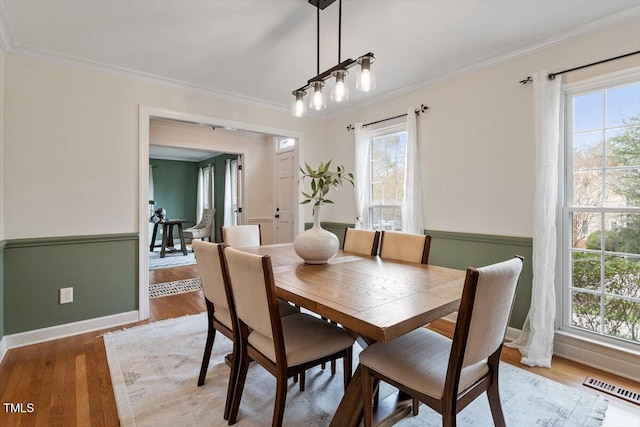 dining room with visible vents, plenty of natural light, ornamental molding, and light wood finished floors