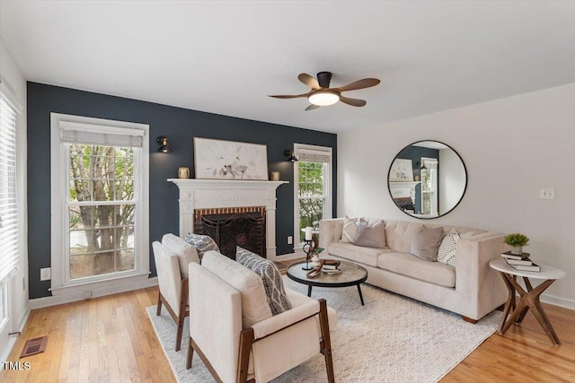 living area with plenty of natural light, a fireplace, visible vents, and light wood finished floors