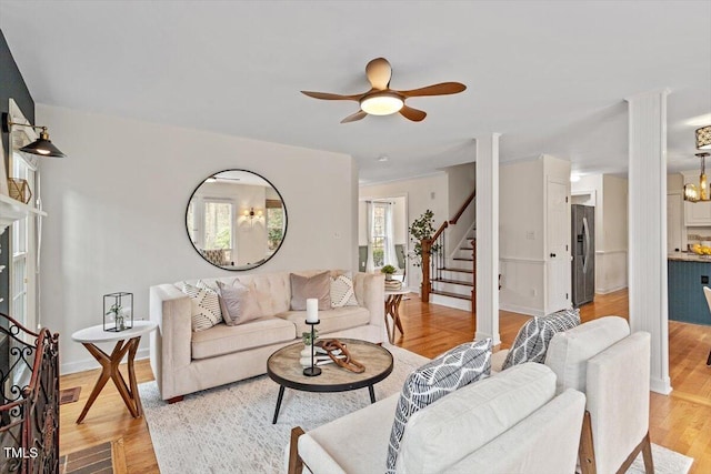 living area with light wood-type flooring, stairway, and a ceiling fan