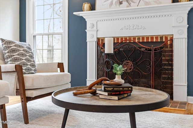 sitting room featuring a brick fireplace and wood finished floors