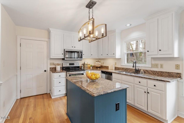 kitchen with dark stone countertops, appliances with stainless steel finishes, white cabinetry, and a sink